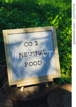 Letter board with text CO2 NEUTRAL FOOD on background of garden bed with green herb parsley. Organic farming, produce local vegetables concept. Supporting local farmers 123775734