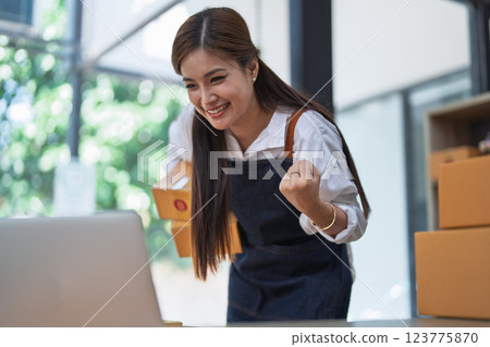 Excited young woman celebrating success while using computer laptop to see data delivery products customer profit Selling products of This month. 123775870
