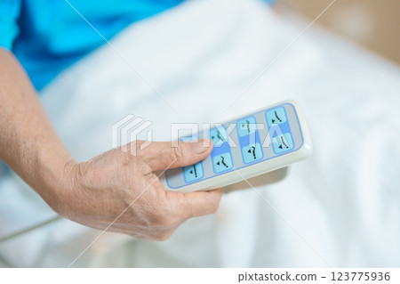 Elderly asian Woman patient hand using remote control for adjust level bed in hospital room. Happy Senior illness resting on comfortable electric bed in modern hospital Elderly asian Woman patient hand using remote control for adjust level bed in hospital room. Happy Senior illness resting on comfortable electric bed in modern hospital 123775936