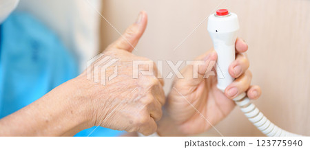 Elderly woman Patient hand holding and pressing emergency button in hospital room, calling nurse in emergency case. Professional Medical system and Safety Alert 123775940