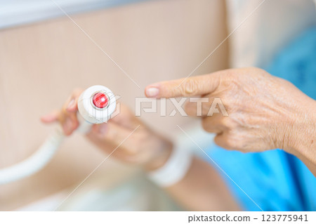 Elderly woman Patient hand holding and pressing emergency button in hospital room, calling nurse in emergency case. Professional Medical system and Safety Alert Elderly woman Patient hand holding and pressing emergency button in hospital room, calling nurse in emergency case. Professional Medical system and Safety Alert 123775941