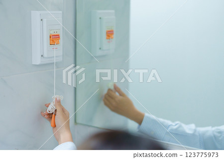 woman Patient hand holding and pulling emergency button in toilet of hospital room, calling nurse in emergency case. Professional Medical system and Safety Alert woman Patient hand holding and pulling emergency button in toilet of hospital room, calling nurse in emergency case. Professional Medical system and Safety Alert 123775973