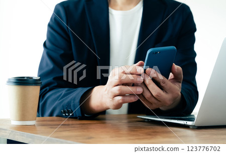 A man who operates a computer and a smartphone A man who operates a computer and a smartphone 123776702