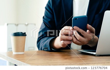 A man who operates a computer and a smartphone A man who operates a computer and a smartphone 123776704