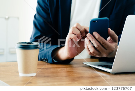 A man who operates a computer and a smartphone 123776707