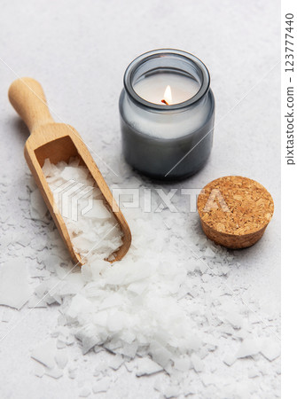 Magnesium flakes with wooden scoop and lit candle creating relaxing atmosphere 123777440