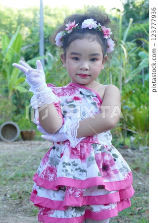Little girl in flower dress on a swing in the garden 123777936