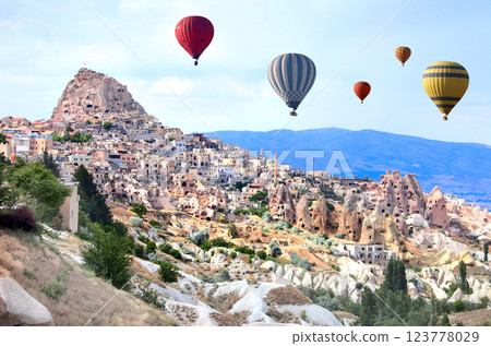 The balloon flight, famous tourist attraction of Cappadocia. Air balloons and carved houses in rock in Pigeon Valley, Uchisar, Cappadocia, Anatolia, Turkey 123778029
