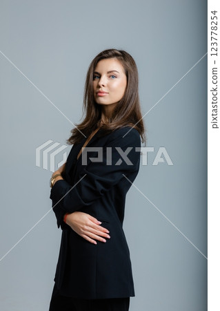 Businesswoman posing barefoot wearing black suit and lace bra in studio 123778254
