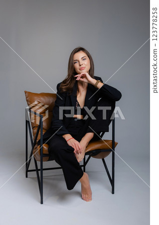 Young businesswoman posing barefoot sitting on a modern chair 123778258