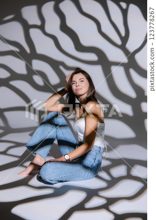 Young woman posing sitting on floor with projected shadows Young woman posing sitting on floor with projected shadows 123778267