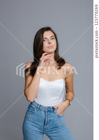 Fashion model posing with white corset and blue jeans looking over shoulder Fashion model posing with white corset and blue jeans looking over shoulder 123778269