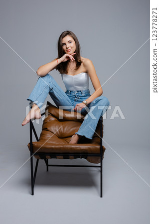 Young woman sitting on modern armchair touching her hair 123778271