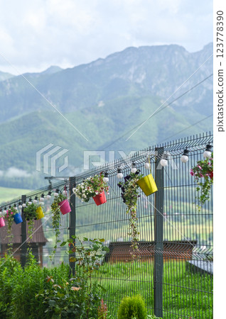 Flower pots attached to a metal fence. Calibrachoa hybrids. vertical Flower pots attached to a metal fence. Calibrachoa hybrids. vertical 123778390