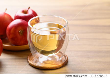 Glass of apple cider and red apple fruit on wooden background Glass of apple cider and red apple fruit on wooden background 123778596