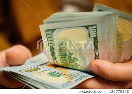 Man counting US dollar banknotes, close up. Cash savings and financial wealth concept Man counting US dollar banknotes, close up. Cash savings and financial wealth concept 123779358