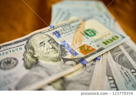 Close-up of US hundred dollar bills stacked on brown fabric surface. Concept of cash transactions, finance, banking and business 123779359