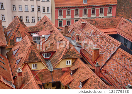 Scenic aerial view of historic European rooftops covered with red clay tiles and chimneys. Old town architecture and traditional cityscapes in European city. Panoramic view of Graz, Austria 123779388