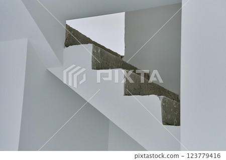 Unfinished concrete staircase in modern minimalist interior. New apartment with raw construction elements and white walls. Building under repair Unfinished concrete staircase in modern minimalist interior. New apartment with raw construction elements and white walls. Building under repair 123779416
