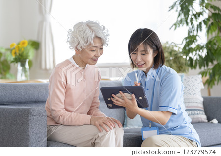 護理人員正用平板電腦聆聽一位老年婦女的傾訴 123779574