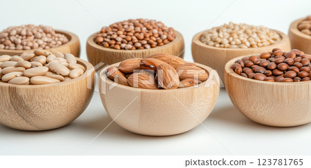 Wooden bowls filled with various grains, legumes, and almonds on white background 123781765