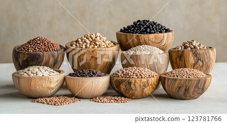 Wooden bowls filled with various grains and legumes arranged on neutral surface 123781766