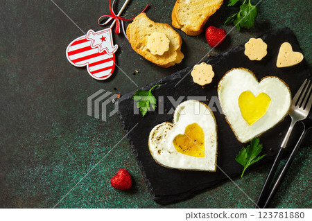 Breakfast on Valentine's Day or brunch. Heart shape fried egg on slate plate. Top view flat lay. Copy space. 123781880