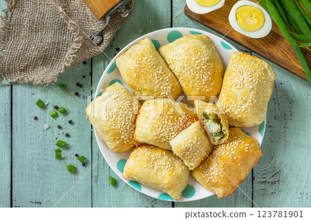 Ukrainian or Russian cuisine. Baked small pies with egg and green onions, spring vitamin baked goods. Top view flat lay. 123781901