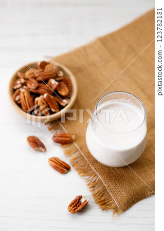 Pecan milk in a glass with raw pecan nuts on wooden table. 123782181