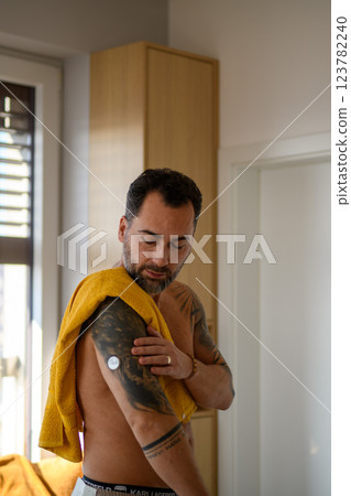 Diabetic man checking his CGM sensor after shower. 123782240