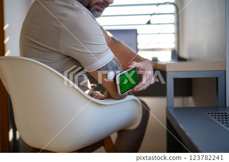 Man with CGM sensor is checking blood glucose level using smartphone app. 123782241