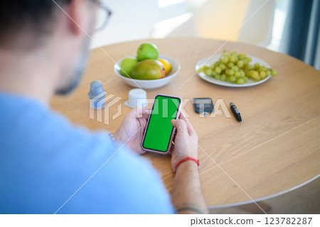 Man is checking blood glucose level using smartphone app. 123782287