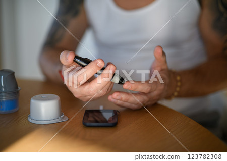 Diabetic man checking his blood sugar at home. Diabetic man checking his blood sugar at home. 123782308
