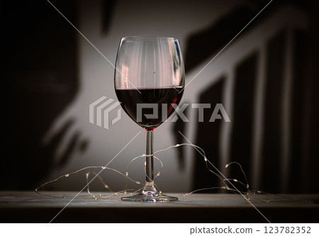 Glass of rich red wine with warm, elegant ambiance. 123782352