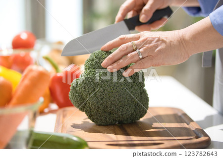 Hands of a middle-aged woman cutting vegetables 123782643