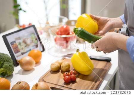 Middle woman cooking while looking at a tablet 123782676
