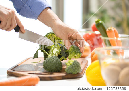 Hands of a middle-aged woman cutting vegetables 123782868
