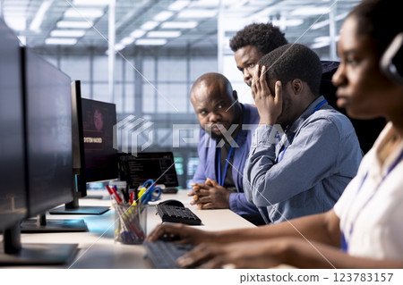 Team of programmers in server farm upset after losing all data after hacker managed to pass firewall. Critical error alert on monitor in data center making IT staff members feel dejected 123783157
