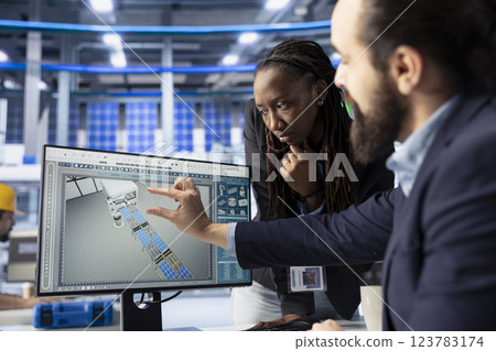 Solar panels plant business partners looking over factory energy consumption on computer. Man and woman in photovoltaics facility managing manufacturing resources using PC Solar panels plant business partners looking over factory energy consumption on computer. Man and woman in photovoltaics facility managing manufacturing resources using PC 123783174
