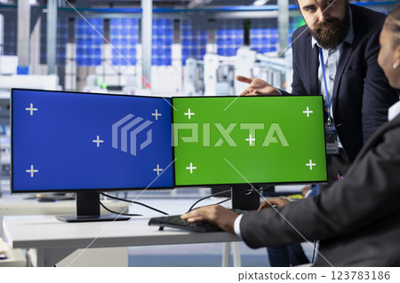 Photovoltaics factory team leader and expert finetuning system settings on green screen PC. Manager works with engineer on solar panels plant assembly lines configuration using chroma key computer 123783186
