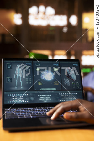 African American male nurse in training reviews anatomy case files in a classic library. Med school student in scrubs studying from database books and research papers in the campus. Close up. African American male nurse in training reviews anatomy case files in a classic library. Med school student in scrubs studying from database books and research papers in the campus. Close up. 123783243