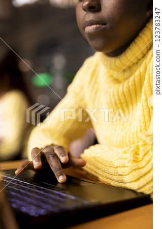 Black scholar does research via internet and taking notes in a library, concentrating on theoretical studies and completing her class notes for the school assignment. Educational work. Close up. 123783247
