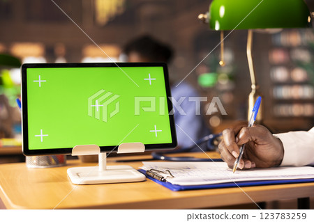 Black male scholar learning to become a doctor next to copy space, taking notes after studying research papers. Young man future doctor sitting at the campus library, med school. Close up. 123783259