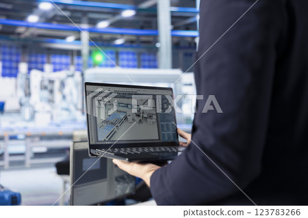 Engineer in photovoltaics factory using tracking software on laptop to diagnose malfunctioning systems. Solar panels manufacturing plant worker uses notebook to reduce downtime Engineer in photovoltaics factory using tracking software on laptop to diagnose malfunctioning systems. Solar panels manufacturing plant worker uses notebook to reduce downtime 123783266