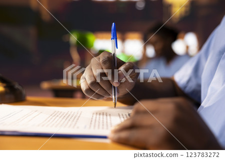 Black male pupil makes notations about practice methods to prepare for an exam, studying at the library to obtain his med school diploma for a medical career. Student does a summary. Close up. 123783272