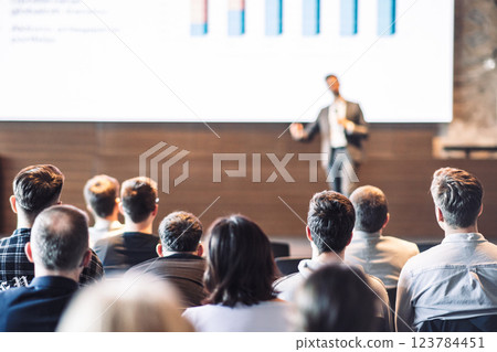 Speaker giving a talk in conference hall at business event. Rear view of unrecognizable people in audience at the conference hall. Business and entrepreneurship concept 123784451