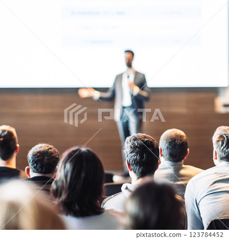 Speaker giving a talk in conference hall at business event. Rear view of unrecognizable people in audience at the conference hall. Business and entrepreneurship concept Speaker giving a talk in conference hall at business event. Rear view of unrecognizable people in audience at the conference hall. Business and entrepreneurship concept 123784452