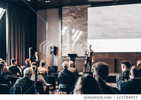 Speaker giving a talk in conference hall at business event. Rear view of unrecognizable people in audience at the conference hall. Business and entrepreneurship concept Speaker giving a talk in conference hall at business event. Rear view of unrecognizable people in audience at the conference hall. Business and entrepreneurship concept 123784453