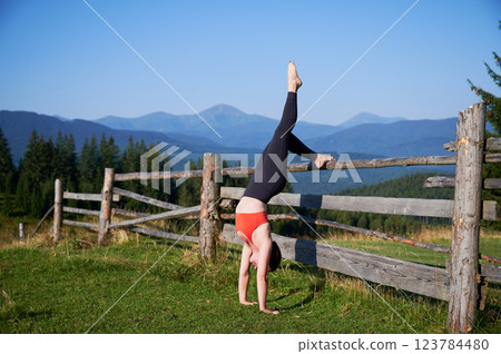 Woman practicing yoga outdoors in the mountains in a serene, natural setting. Female performing yoga pose, with backdrop of beautiful mountain landscape at sunrise or sunset. Woman practicing yoga outdoors in the mountains in a serene, natural setting. Female performing yoga pose, with backdrop of beautiful mountain landscape at sunrise or sunset. 123784480