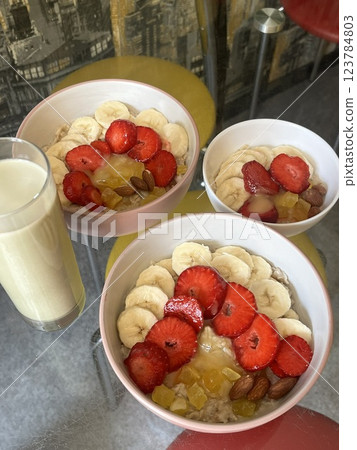 oatmeal with fruits, berries, nuts, honey and milk stands on a glass table, healthy breakfast oatmeal with fruits, berries, nuts, honey and milk stands on a glass table, healthy breakfast 123784803